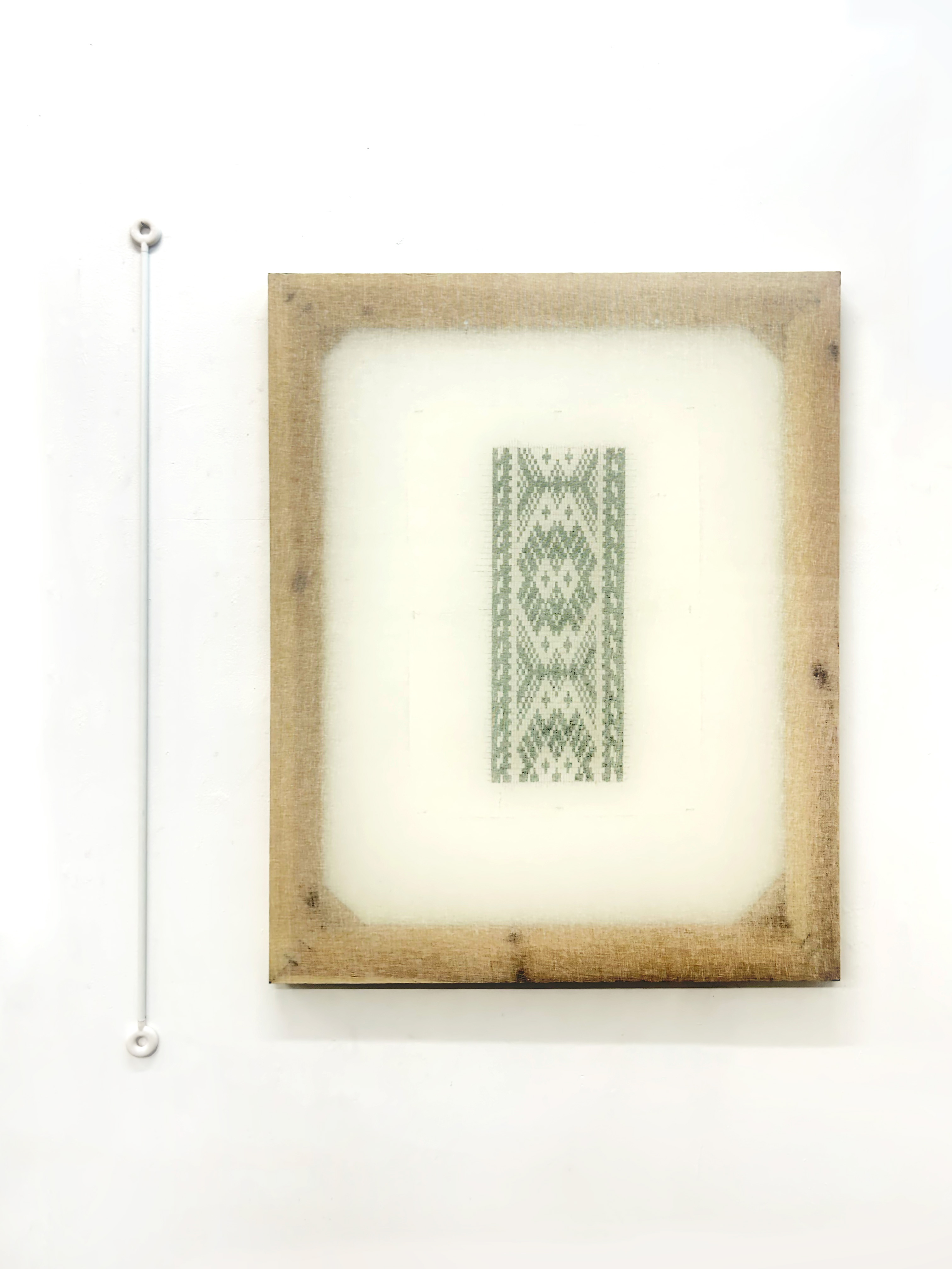 installation: small embroidered green pattern on muslin-stretched pine, with white curtain rod hanging beside
